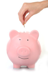 Female hand putting coin into piggy bank isolated on white