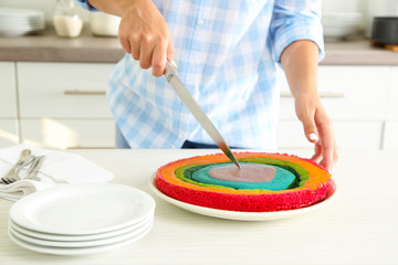 Obraz na płótnie Canvas Young woman making rainbow cake in kitchen