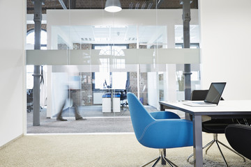 Conference room with blue chair and blurred businessman in the background