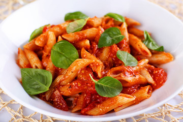 Pasta with tomato sauce and basil on table close up
