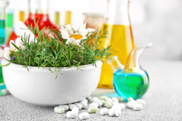 Herbs in mortar, test tubes and pills,  on table, on light background