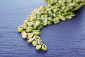 Pile of green coffee beans on wooden table, closeup