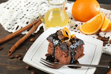 Portion of Cake with Chocolate Glaze and orange on plate, on wooden background