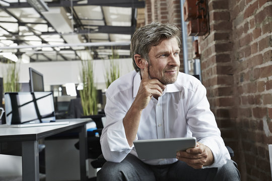 Businessman in office with digital tablet looking to the side