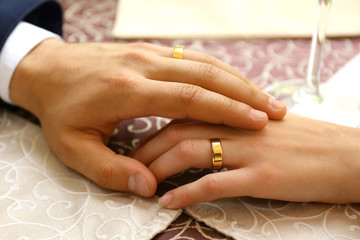 Hands of newlyweds at table in cafe, closeup