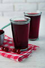 Two glasses with cherry juice on table, on light background