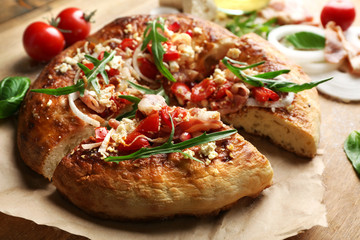 Greek homemade pizza with ham,onion, roasted tomato, creamy feta on wooden table background