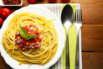 Spaghetti with tomato sauce, paprika and cheese on white plate, on color wooden background