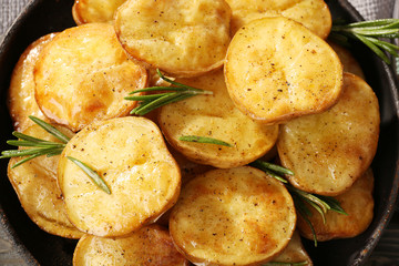 Delicious baked potato with rosemary in frying pan close up