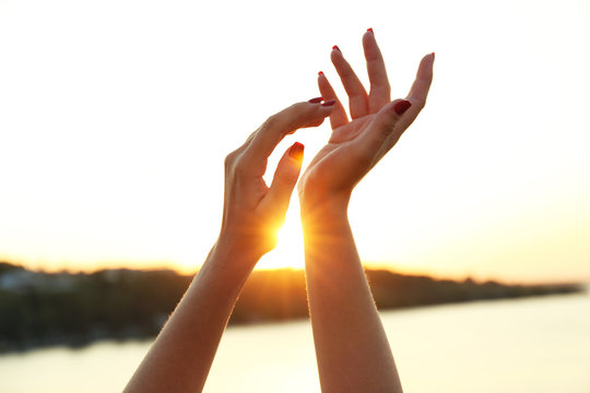 Female hands on sunny sky background