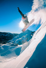 Snowboarder jumping off a cliff off piste, backlit by the sun on © Don Landwehrle
