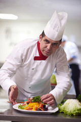 chef in hotel kitchen preparing and decorating food