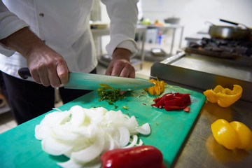 Obraz na płótnie Canvas chef in hotel kitchen slice vegetables with knife