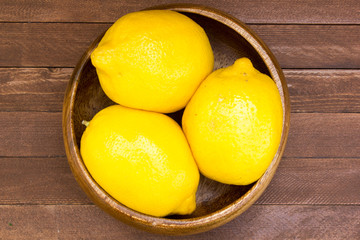 Lemons in plate on wooden background