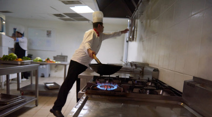 chef in hotel kitchen prepare food with fire
