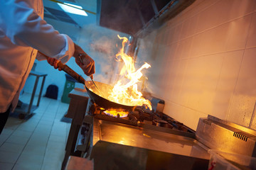 chef in hotel kitchen prepare food with fire