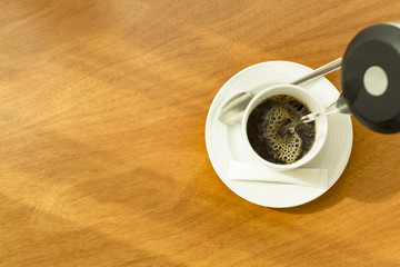 Hot water being poured into a white cup to create a cup of coffee