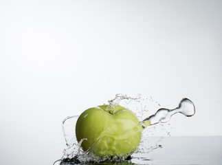Green apple in splash of water on white background