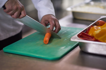 chef in hotel kitchen  slice  vegetables with knife