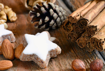 Weihnachtszeit - Zimtstern, Nüsse, Zimtstangen, auf Holz mit Tannenzapfen