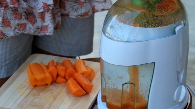 Modern working electrical blender making juices from carrot. raw carrot juice
