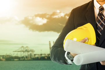 Engineer holding plan paper beside of construction site progress