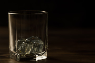 glass of whiskey with ice on a wooden table. Cognac, brandy.