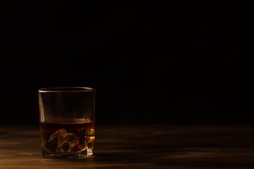 glass of whiskey with ice on a wooden table. Cognac, brandy.