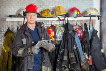 Obraz premium Fireman Holding Digital Tablet At Fire Station