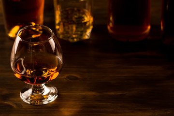glass of whiskey with ice and a bottle on a wooden table. Cognac, brandy.
