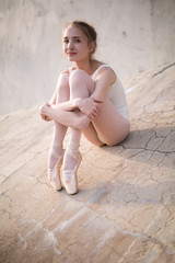 Slim dancer sitting on a concrete surface