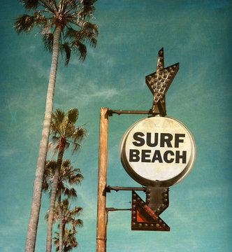 aged and worn vintage photo of surf beach sign with palm trees