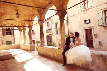 Bride and groom sitting near old building
