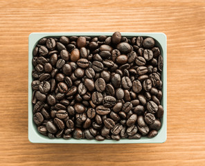 brown coffee beans in cup on wood background