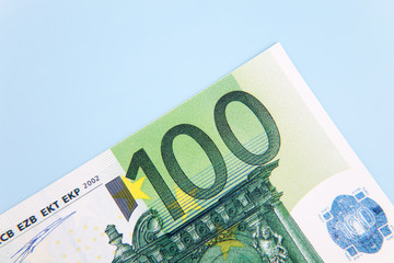 Single 100 euro note on light blue background