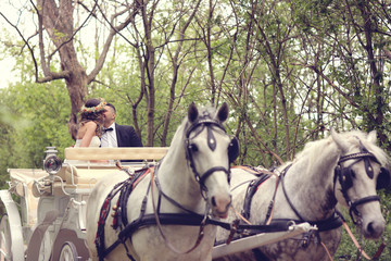 Bride and groom sitting in a white carriage