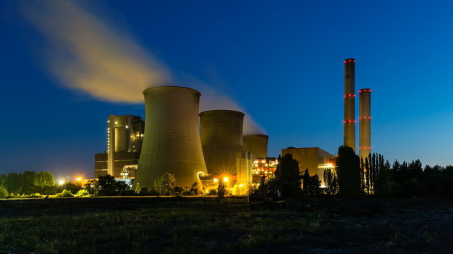 Time lapse sequence of a large coal-fired power plant at night with a lot of steam and deep blue sky.
