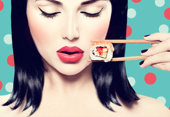 Beautiful woman holding chopsticks with sushi roll