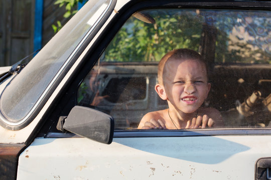 Funny Boy Behind Glass in Old Car Playing Outdoor