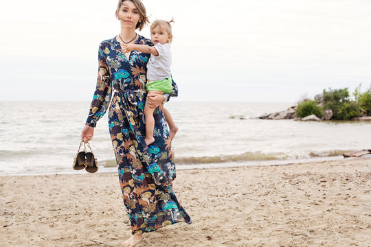 Young Mother and her Little Baby Walking Outdoor on the Sea Shore. Family Love Concept