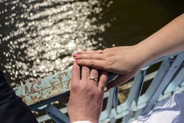The groom and the bride hold hands. On fingers wedding rings