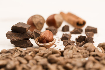 Broken chocolate bar, hazelnut and cinnamon on wooden background, close-up