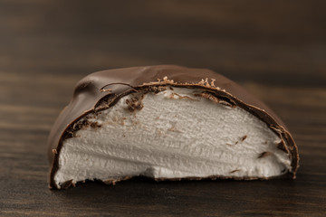 two chocolate covered marshmallows, part of one bitten off, isolated on white background