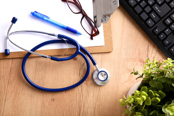 A medical stethoscope near a laptop on a wooden table, on white