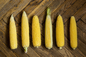 Corn cobs on wooden floor, top view