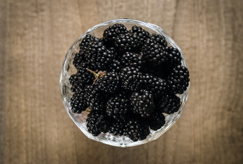 Mulberry fruits in a vase on wooden table, top view