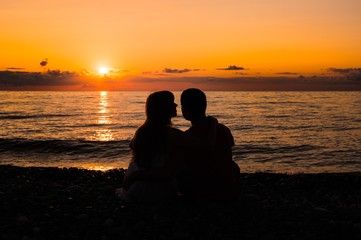 Silhouette of a young romantic couple looking at sunset