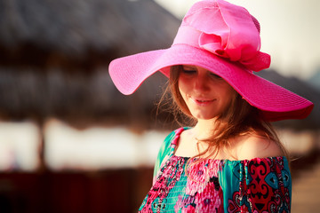 brunette girl in big red hat looks down at defocused background
