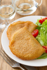 portuguese meat cookies with fresh salad on white dish on brown background