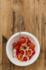 tomato salad with onion in bowl on brown wooden background